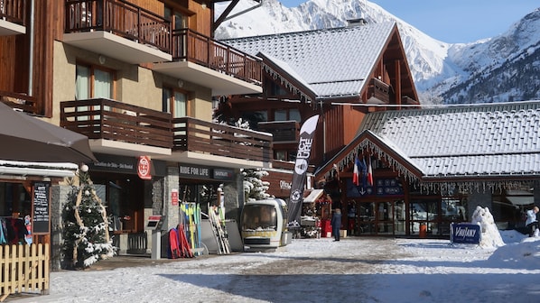 Un edificio de madera con balcones, letreros de alquiler de esquíes y un cartel que indica 'Vaujany'.