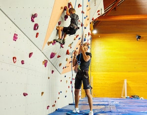 Un espace intérieur dédié à l’escalade, doté de murs rembourrés et d’éléments d’ancrage.