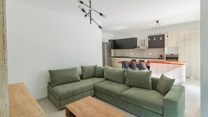 A modern living room with a sectional sofa, a wooden coffee table, and a kitchen in the background.