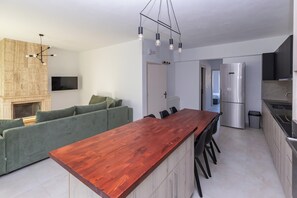 Una cocina moderna con una isla de madera, electrodomésticos integrados y un sofá verde.