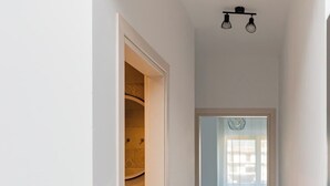 A hallway with a closet, a bed, and a window with blinds.