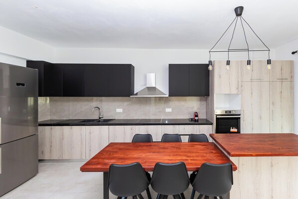 Una cocina moderna con una isla central, armarios negros y un refrigerador de acero inoxidable.