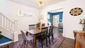 A dining area with a wooden table and chairs, a patterned rug, and a ceiling light fixture. - Historic Cleveland Home - Jacuzzi Tub and Fire Pit (Cleveland)
