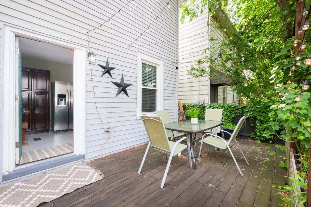 Eine Terrasse mit Tisch und Stühlen, ein Kühlschrank im Inneren und eine Tür zu einer Küche.