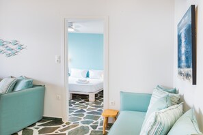 A room with a bed, two sofas, a small stool, and a painting on the wall. - Apartment 'Stella's Studio' with Shared Terrace, Wi-Fi and Air Conditioning (Galissas)