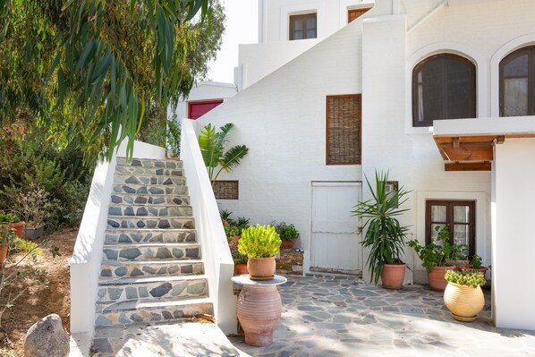 A white building with a stone staircase, potted plants, and a door.