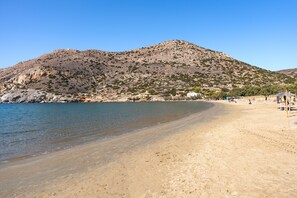 En strand med ett berg i bakgrunden, en sandstrand och några få personer.