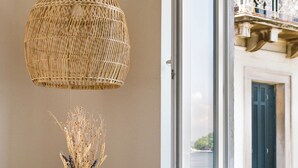 Un comedor con una mesa, sillas, una lámpara de mimbre colgante y una ventana con vistas a un balcón.