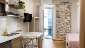Una cocina moderna con comedor, televisor y vista al mar desde un balcón.