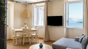 Una sala de estar moderna con comedor, televisor de pantalla plana y un ventanal con vistas a la montaña.