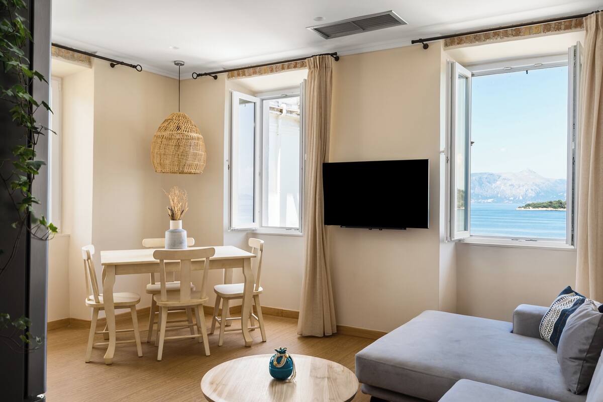 Een moderne woonkamer met een eethoek, een flatscreen-tv en een groot raam met uitzicht op bergen.