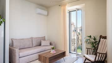 Un soggiorno moderno con un divano, un tavolino in legno, una poltrona a dondolo e una porta scorrevole in vetro che dà su un balcone.