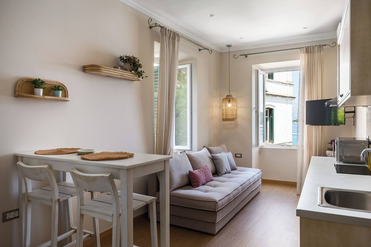Een moderne keuken met een eethoek, een bank en een raam met gordijnen.