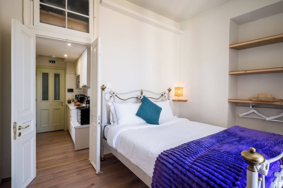Een slaapkamer met een bed, nachtkastje, lamp en kledingkast.