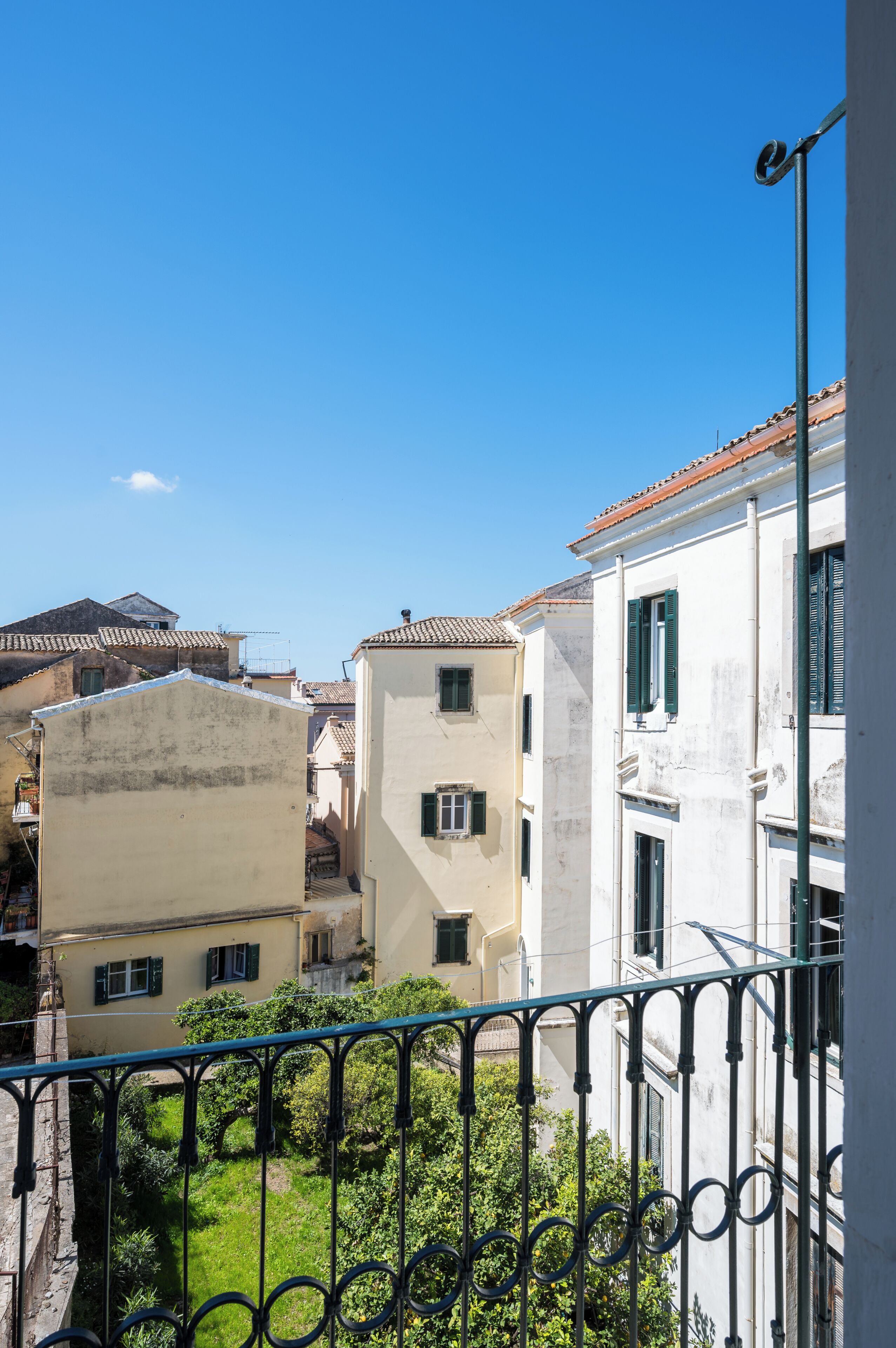 A residential area with buildings, a balcony with a metal railing, and a clear blue sky.