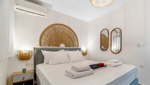 A bedroom with a bed, bedside tables, a wall-mounted air conditioner, and two wall-mounted mirrors. - Studio Apartment 'Oceanida Terpsis Lyxury Suite' with Sea View, Wi-Fi and Air Conditioning (Lefkada)