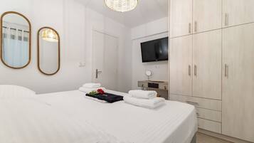 A hotel room with a bed, two mirrors, a television, and a wardrobe.