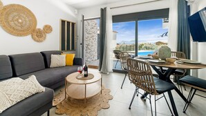A modern living room with a sofa, coffee table, and dining area. - Studio Apartment 'Oceanida Terpsis Lyxury Suite' with Sea View, Wi-Fi and Air Conditioning (Lefkada)