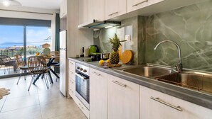 A modern kitchen with a large window, a dining area with chairs, and a view of the outside. - Studio Apartment 'Oceanida Terpsis Lyxury Suite' with Sea View, Wi-Fi and Air Conditioning (Lefkada)