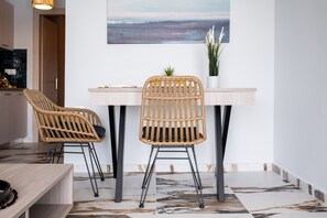 A dining area with two wicker chairs, a table, and a potted plant.
