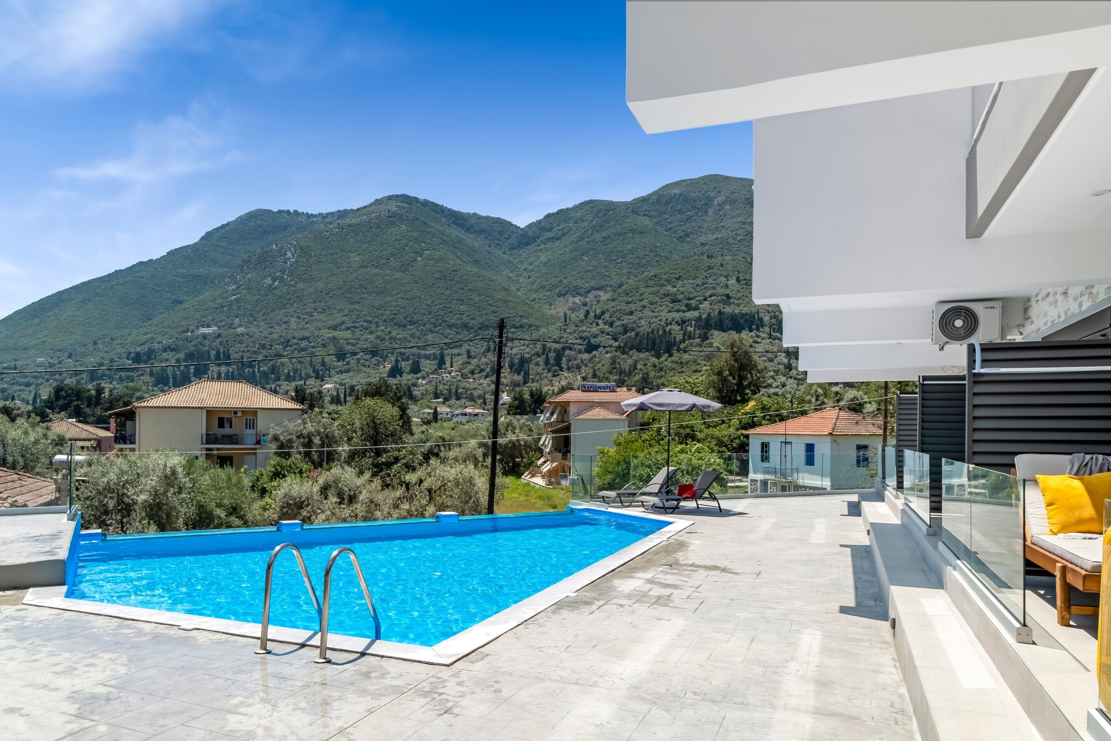 Une piscine sur le toit offrant une vue dégagée sur les montagnes, un bâtiment moderne et un espace de détente.