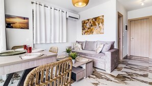 A modern living room with a sofa, dining table, and a hanging light fixture. - Studio Apartment 'Oceanida Thalia Lyxury Suite' with Sea View, Wi-Fi and Air Conditioning (Lefkada)