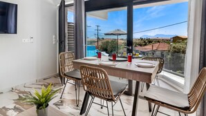 A balcony with a dining table set for four, wicker chairs, and a potted plant. - Studio Apartment 'Oceanida Thalia Lyxury Suite' with Sea View, Wi-Fi and Air Conditioning (Lefkada)