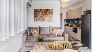 A modern living room with a sofa, a dining table, and a kitchen area with a refrigerator. - Studio Apartment 'Oceanida Thalia Lyxury Suite' with Sea View, Wi-Fi and Air Conditioning (Lefkada)