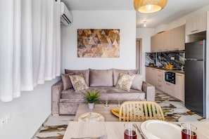 Una sala de estar moderna con un sofá, una mesa de comedor y una zona de cocina con un refrigerador.
