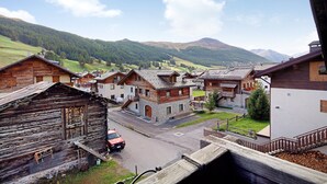 Un village traditionnel avec des maisons en bois, une rue et une chaîne de montagnes en arrière-plan.