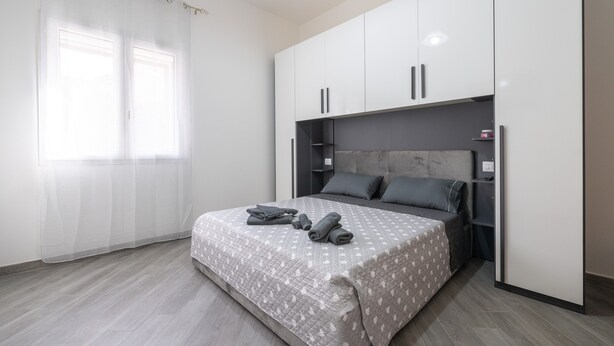 Un dormitorio con cama, armario y ventana con cortinas.
