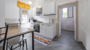 Una cocina moderna con armarios blancos, horno empotrado y cafetera.