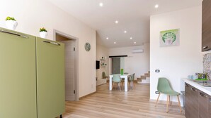 A modern kitchen with a green refrigerator, a dining area with a white table and chairs, and a staircase leading to another level. - Holiday Home "Sefy Mare a Selinunte" with Sea View, Balcony & Wi-Fi (Marinella)