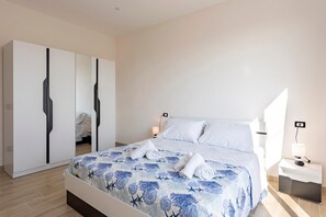 Une chambre à coucher bien rangée, avec un lit, une armoire, une table de chevet et une lampe fixée au mur.