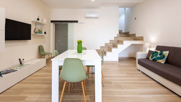 A modern living space with a dining area, a sofa, a TV, and a staircase. - Holiday Home "Sefy Mare a Selinunte" with Sea View, Balcony & Wi-Fi (Marinella)