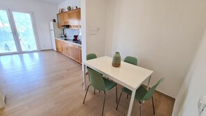 A modern kitchen with wooden cabinets, a white countertop, and a dining table with green chairs.