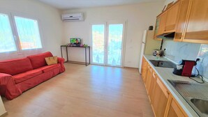 A compact kitchen with a red sofa, a small table, and a window with a view. - Apartment 'Spiagge Bianche' with Sea View, Balcony and Air Conditioning (Portoferraio)
