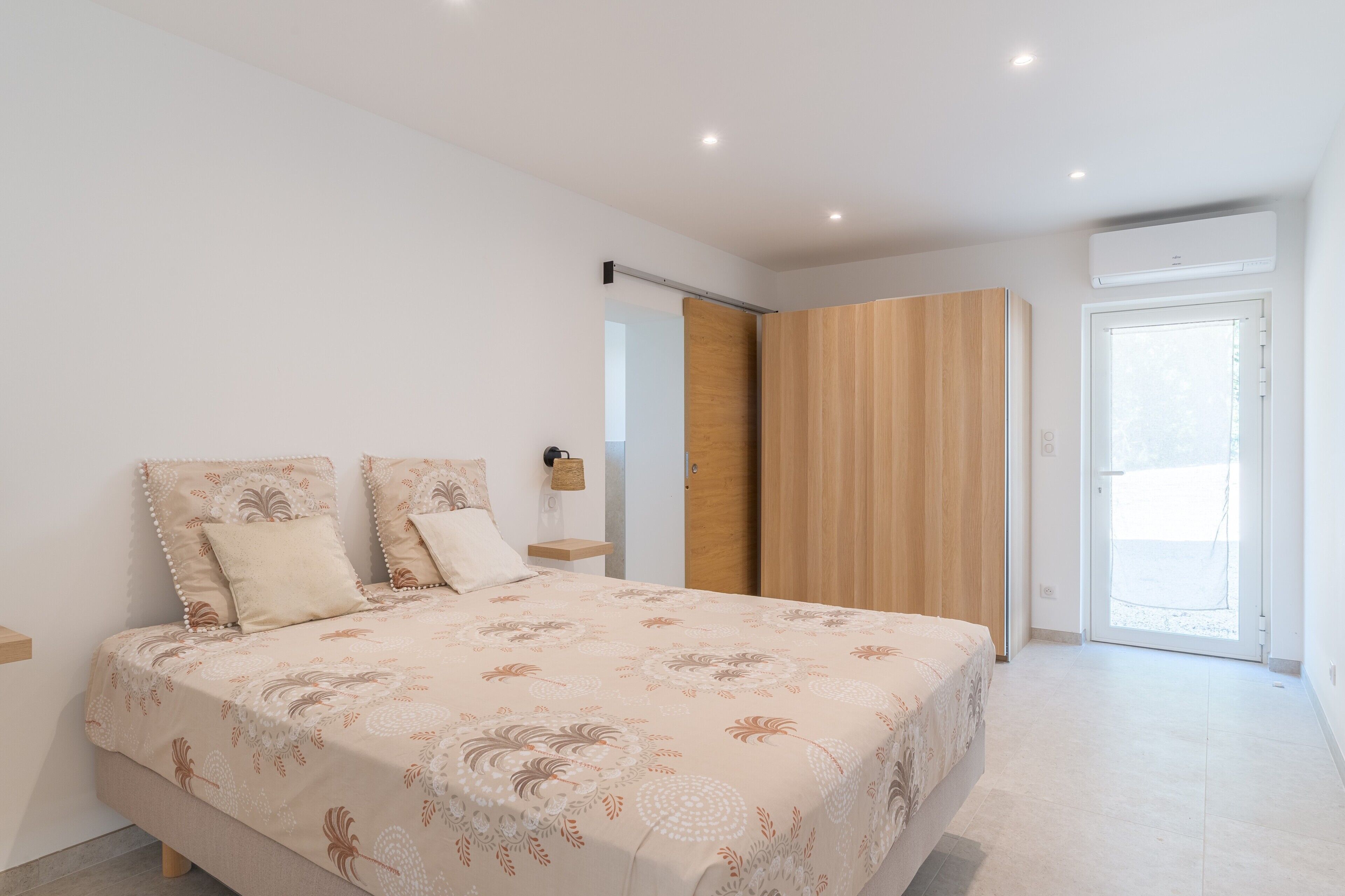 Una camera da letto con un letto, un armadio, un comodino e una porta che dà su un balcone.