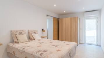 Una camera da letto con un letto, un armadio, un comodino e una porta che dà su un balcone.