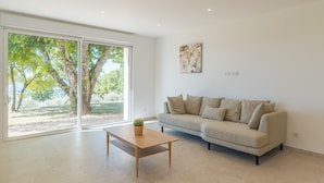 En moderne stue med sofa, sofabord og en stor skydedør til et udendørs område.
