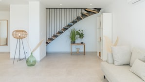 En moderne stue med trappe, sofa, konsolbord og en potteplante.
