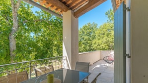 En udendørs terrasse med et glasbord, stole og en pergola.