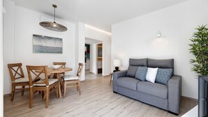 A modern living room with a grey sofa, wooden dining table, and chairs.