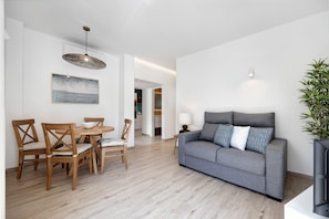 Ein modernes Wohnzimmer mit grauem Sofa, Esstisch aus Holz und Stühlen.