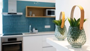 Een moderne keuken met een blauwe spatwand, witte kasten en een magnetron op een plank.