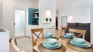 Een moderne keuken met een eethoek, met een witte deur, turquoise spatwand en een grijze bank.
