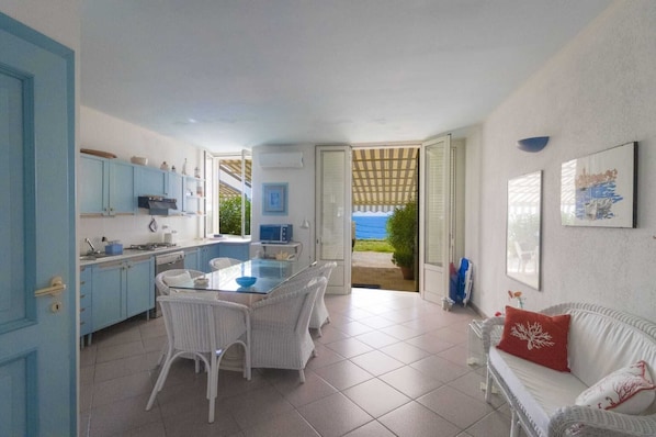 A kitchen with a dining area, a white wicker sofa, and a view of the outdoors.