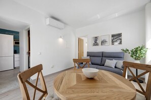 Un salon moderne avec une table à manger ronde en bois, un canapé gris et une plante en pot.