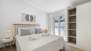 Une chambre à coucher avec un lit, des tables de chevet, une armoire et une vue par la fenêtre.
