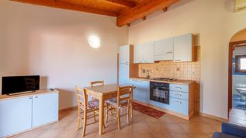 Una cocina compacta con una mesa de comedor, sillas, un televisor sobre un mueble y un salpicadero de azulejos.